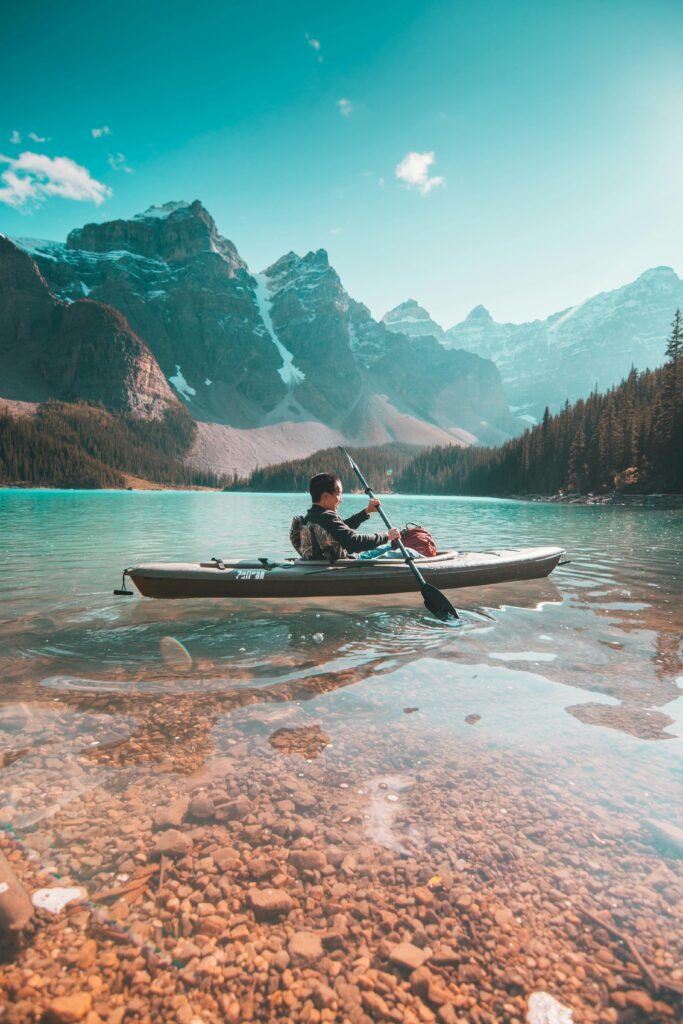 A lone kayaker paddles on the serene waters of Moraine Lake with stunning mountain scenery in Banff, Alberta.